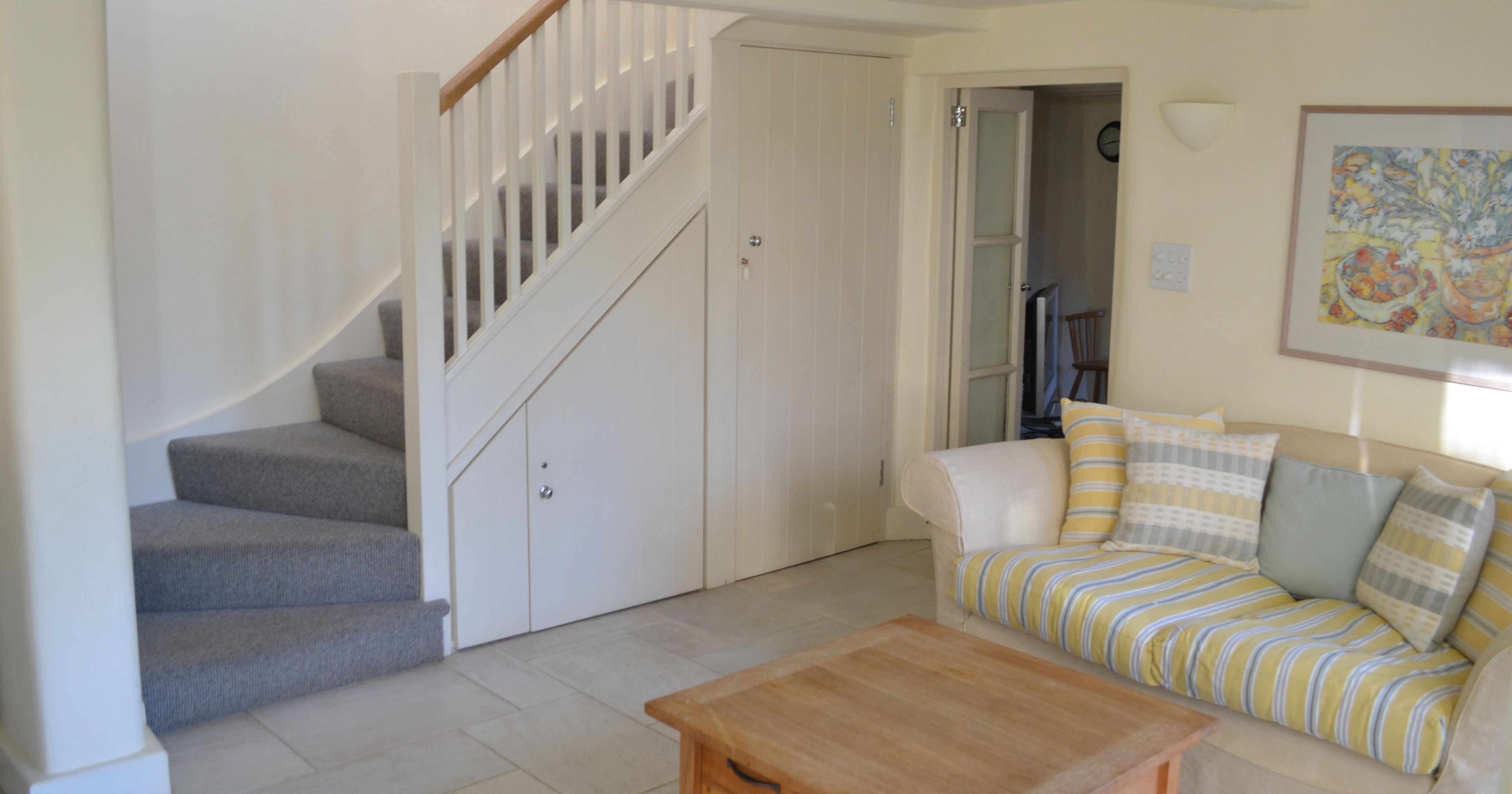 Cozy living room with striped sofa, wooden coffee table, and staircase with storage underneath