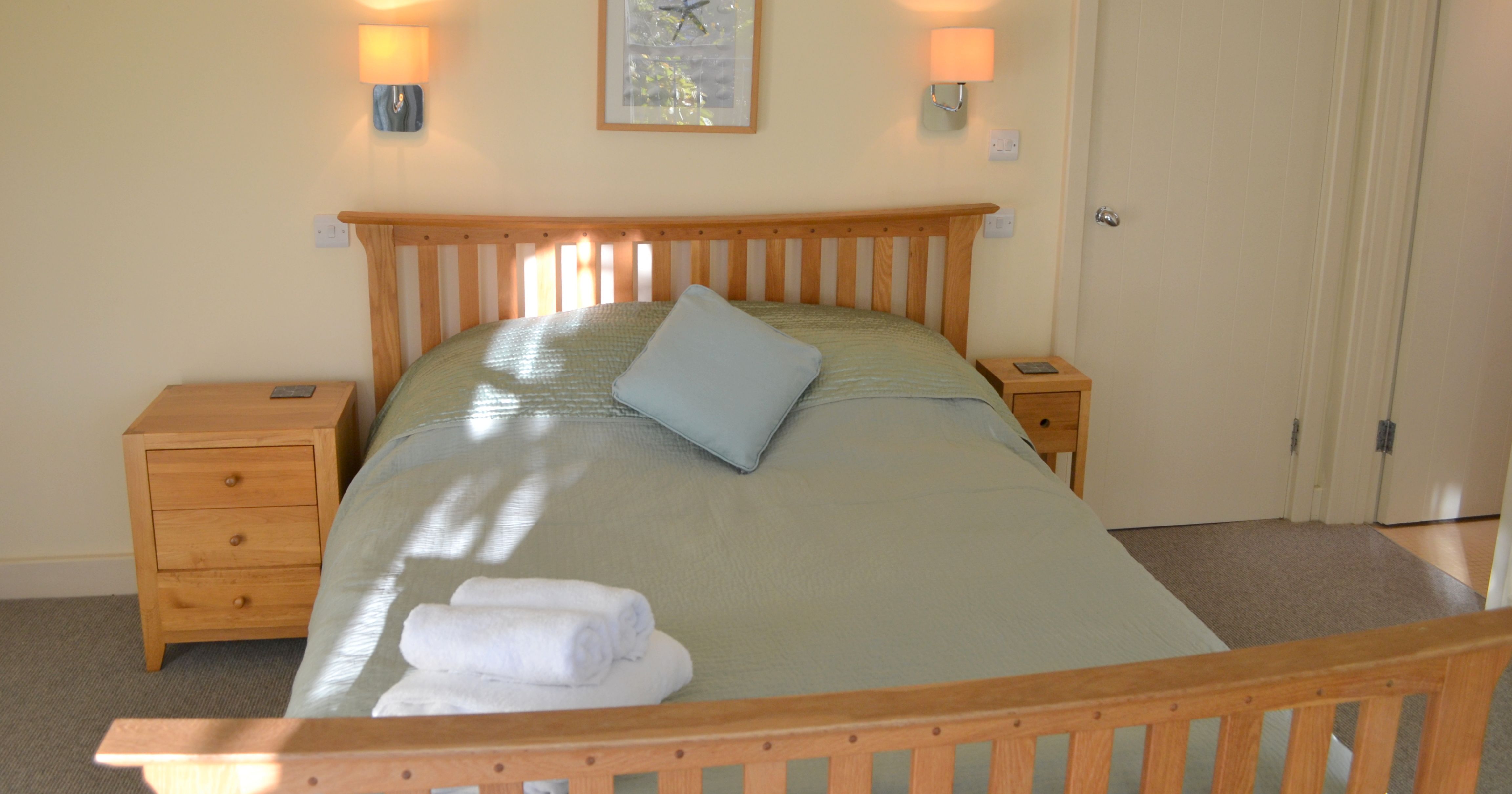 Cozy bedroom with a wooden bed, bedside tables, and light green bedding