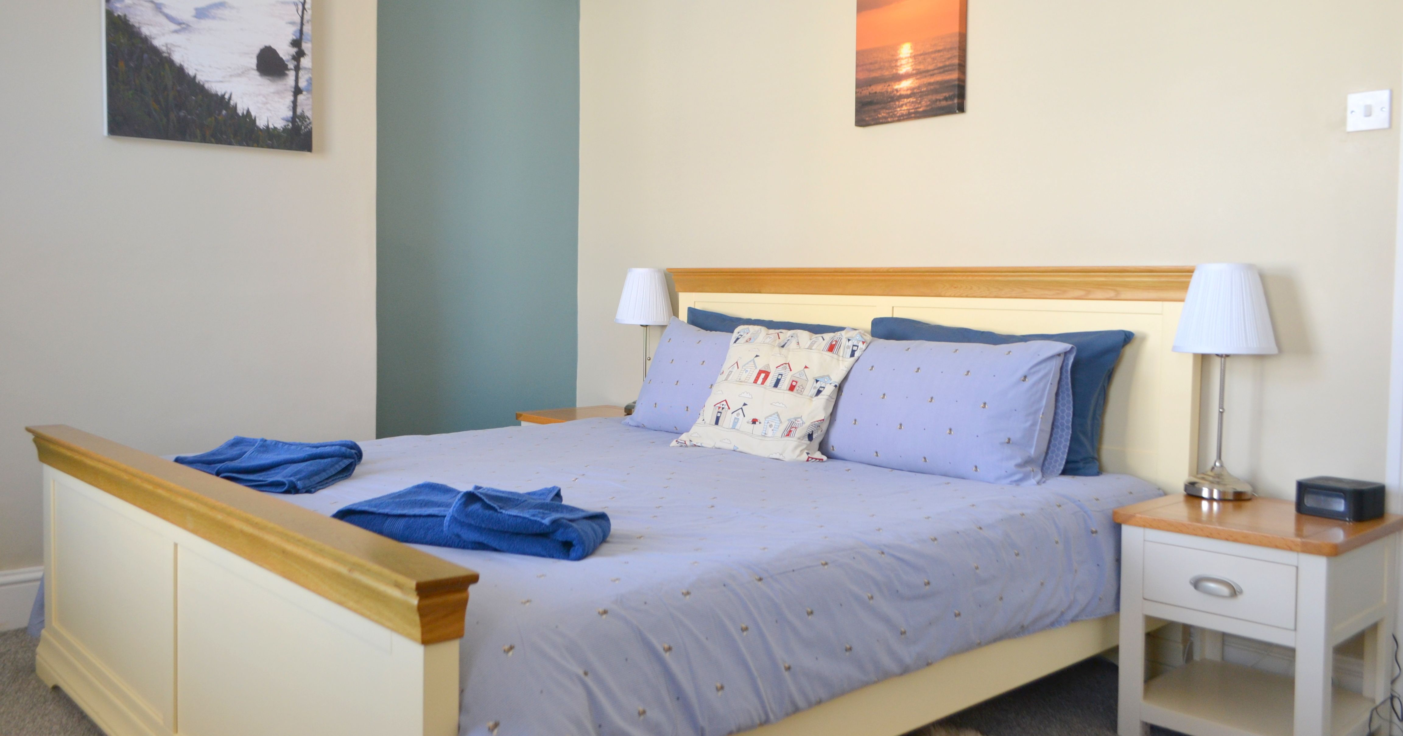 Cozy double bedroom with blue bedding and two bedside tables with lamps.