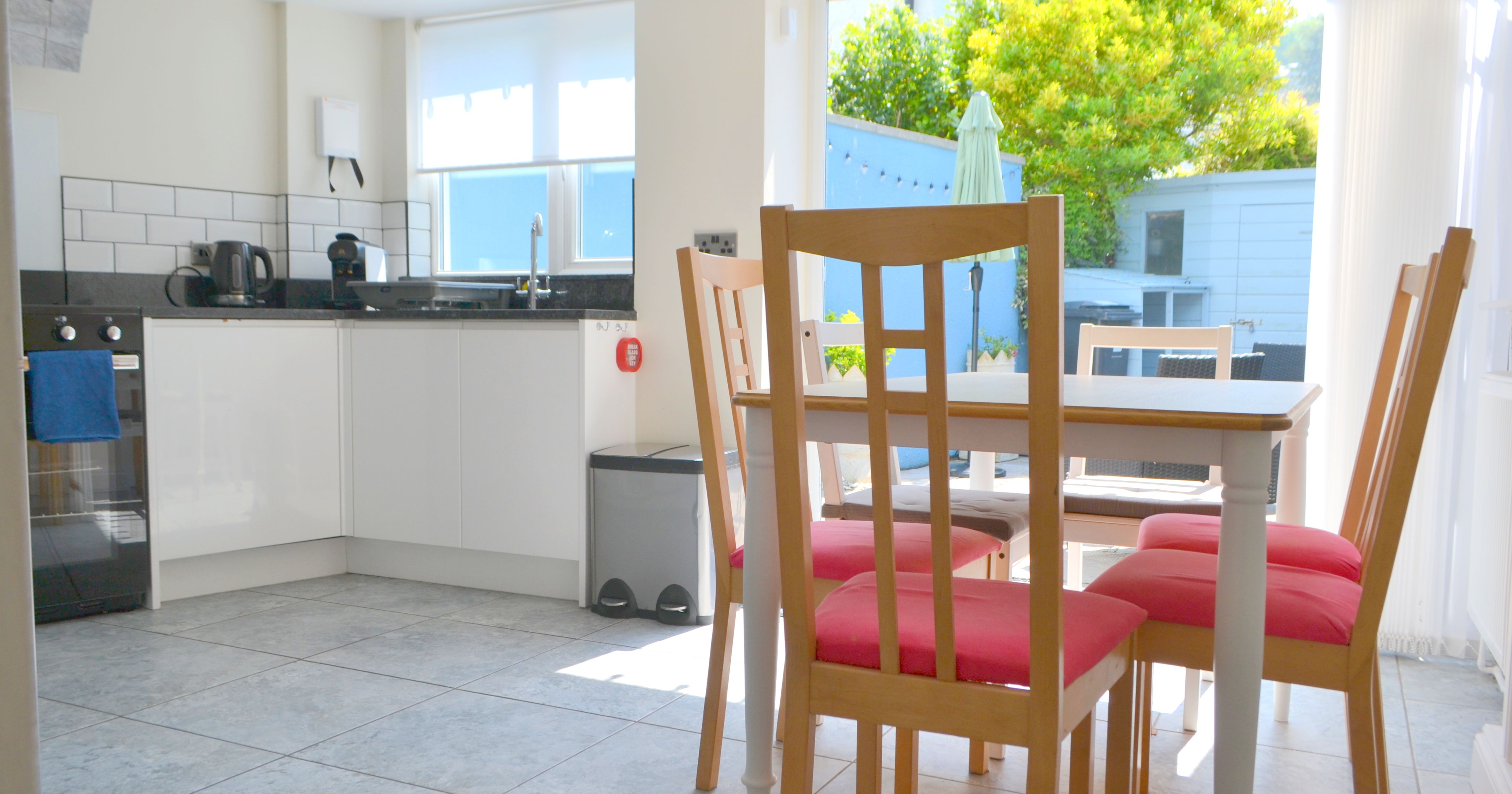 Modern kitchen and dining area with wooden chairs and large window overlooking garden