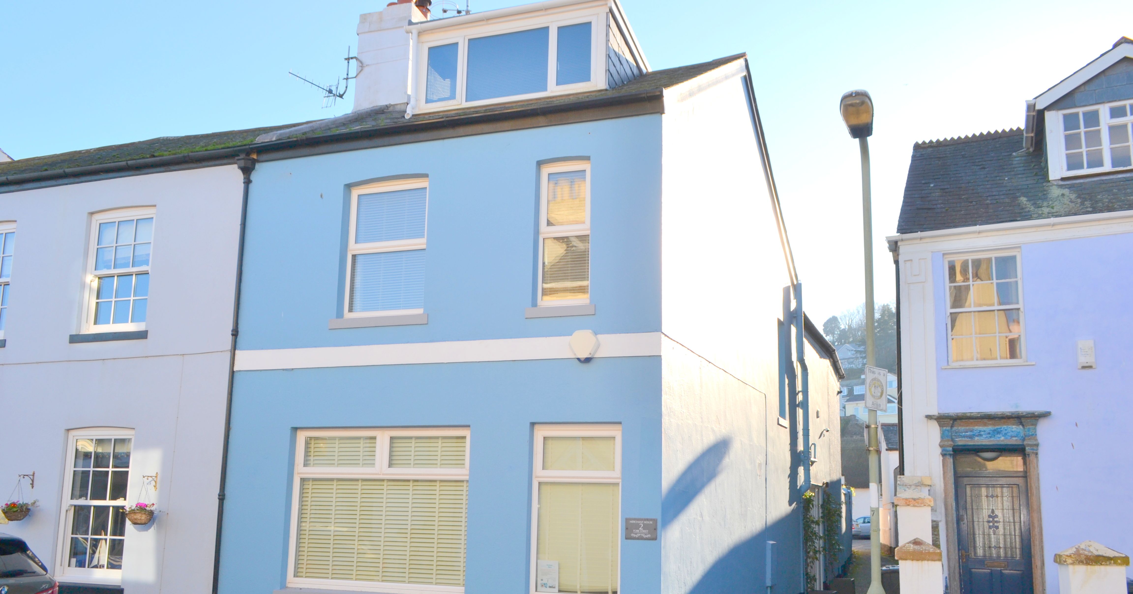 A light blue painted end-terrace house with white window frames and a dormer loft window in Shaldon.