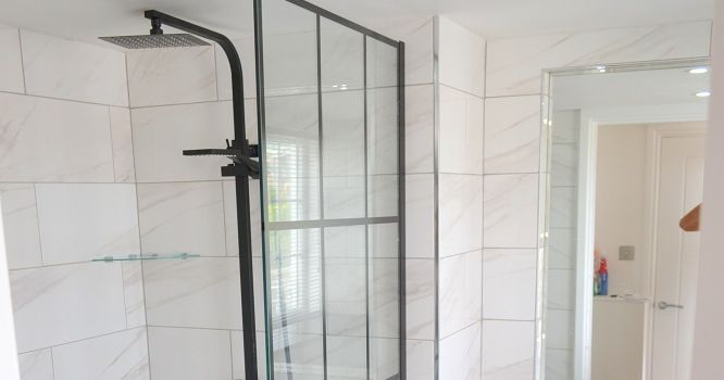Modern bathroom with walk-in shower featuring glass partition and rain shower head