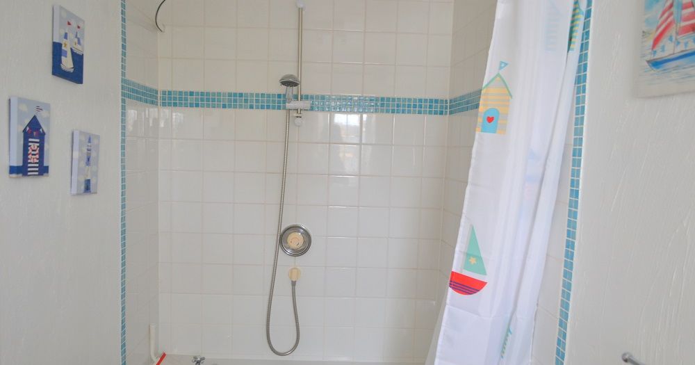 Family bathroom with white bathtub, shower, and nautical-themed decorations