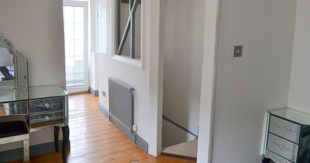 Mirrored dresser and nightstand in a bright master bedroom with wooden floors