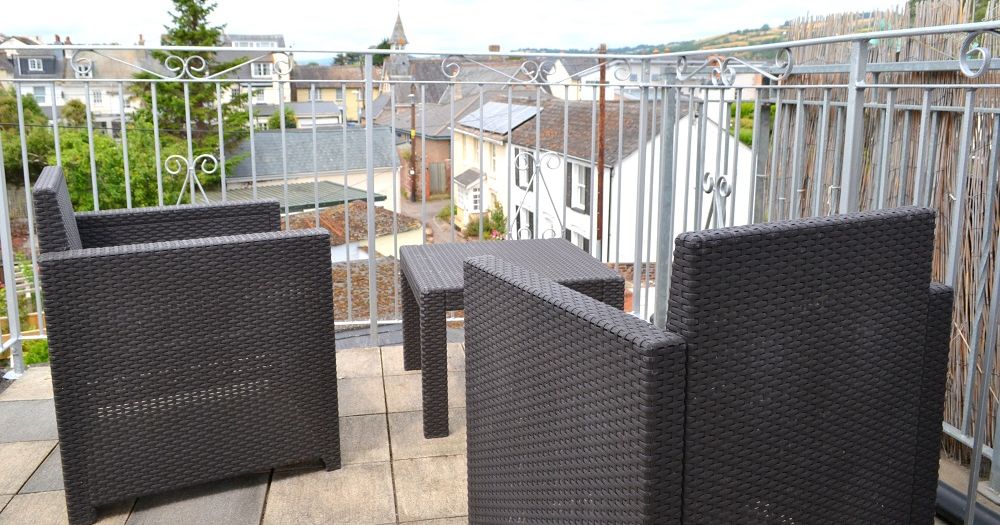 Rooftop terrace with wicker chairs and a small table overlooking residential buildings
