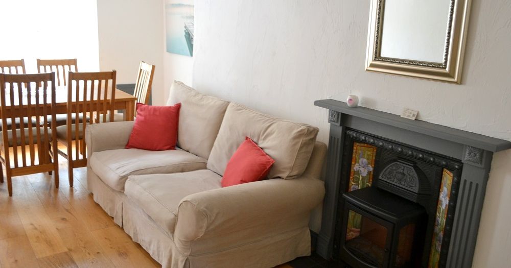 Bright sitting room with beige sofa, dining table, and decorative fireplace