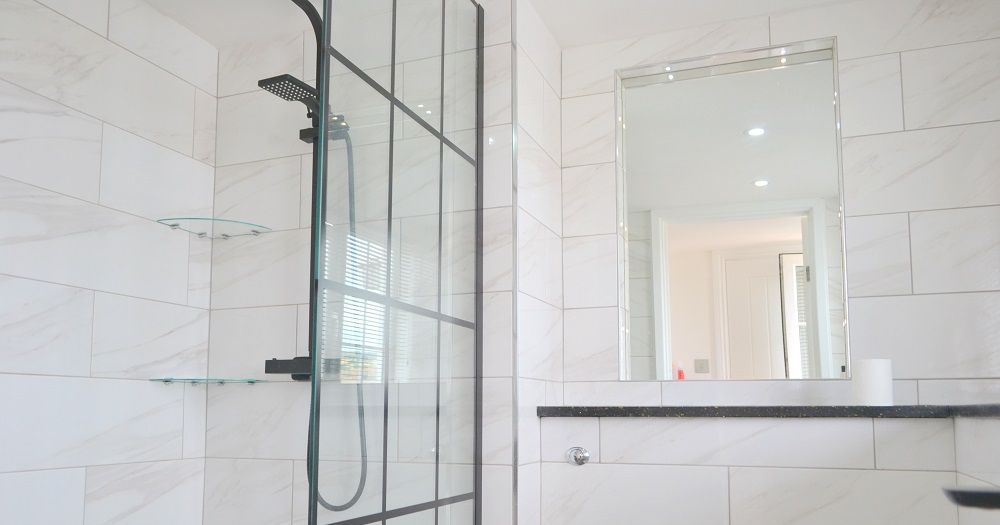 Modern shower room with glass panel and white tiled walls
