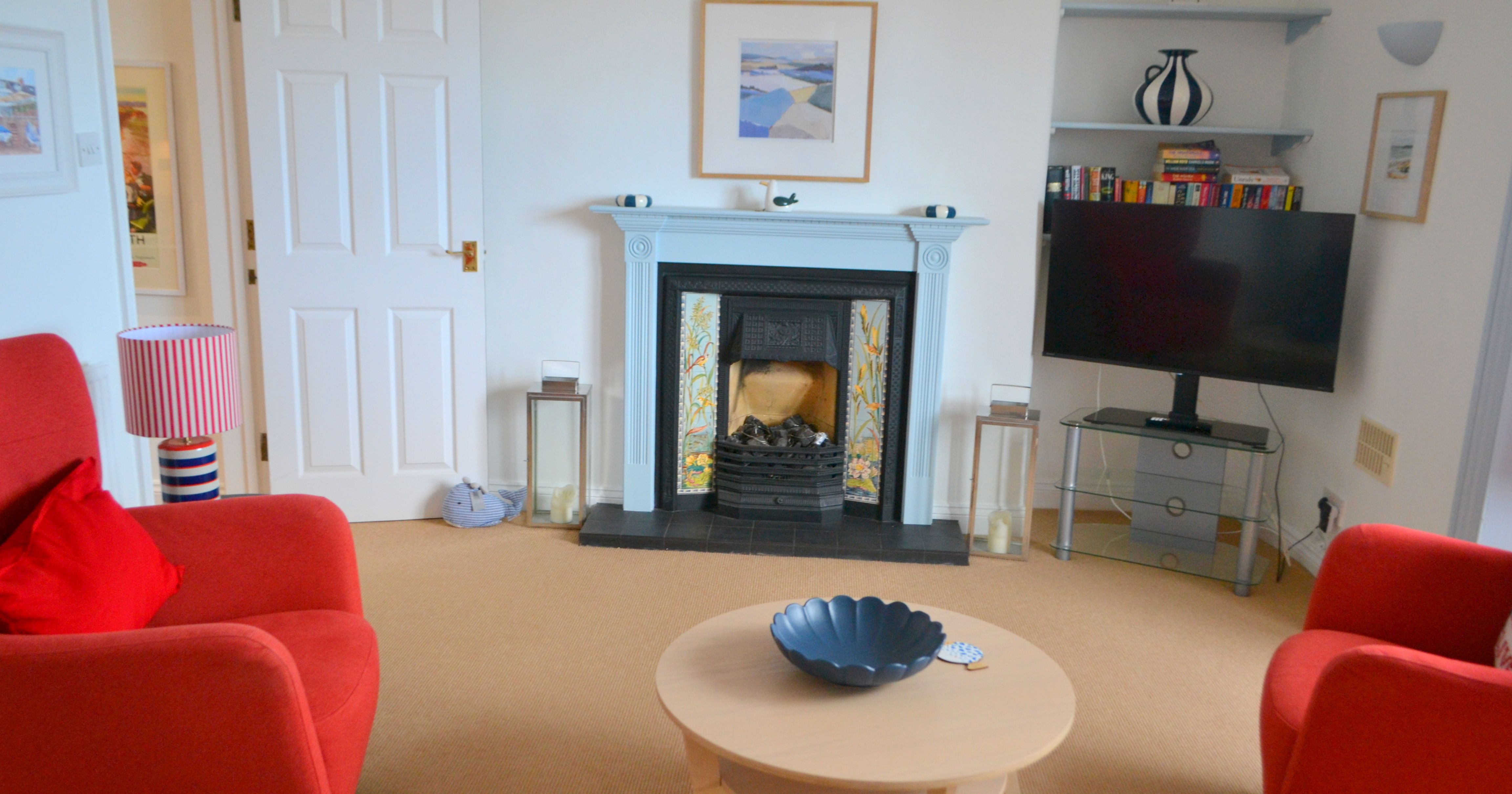 Living room with red armchairs, light blue fireplace, modern decor and TV