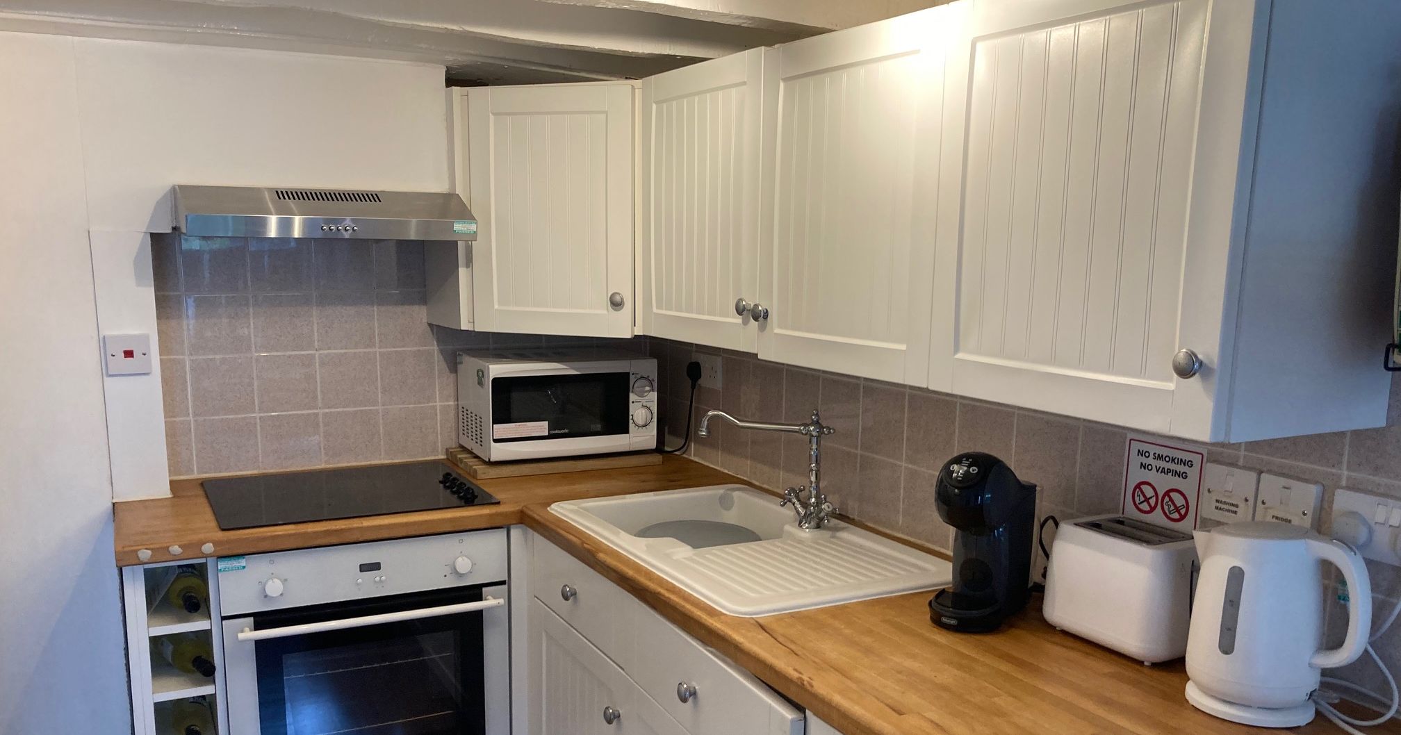 Modern kitchen with appliances including coffee machine, kettle, toaster, and microwave.