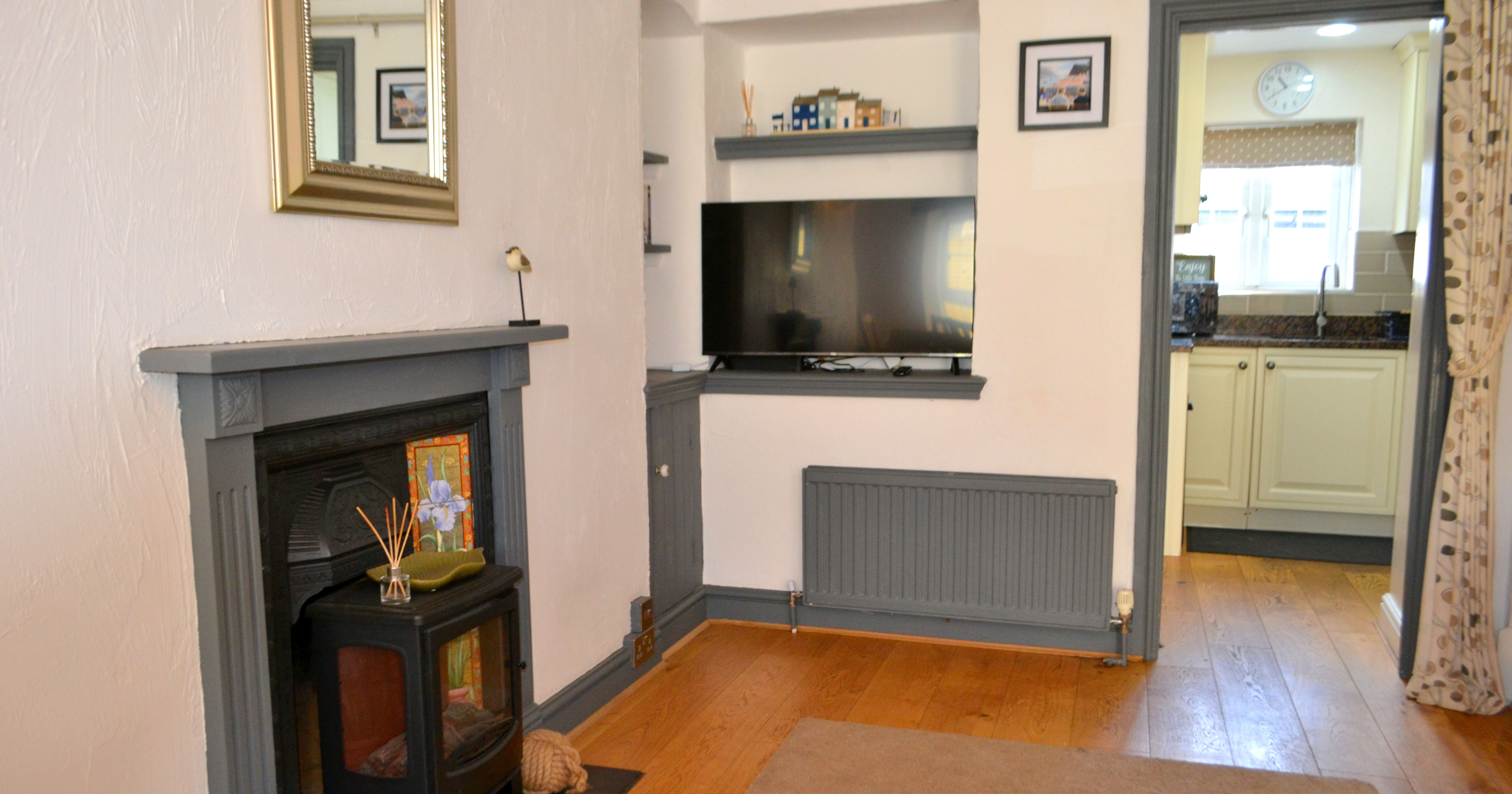 Cozy living room with fireplace, TV, and a view into the kitchen