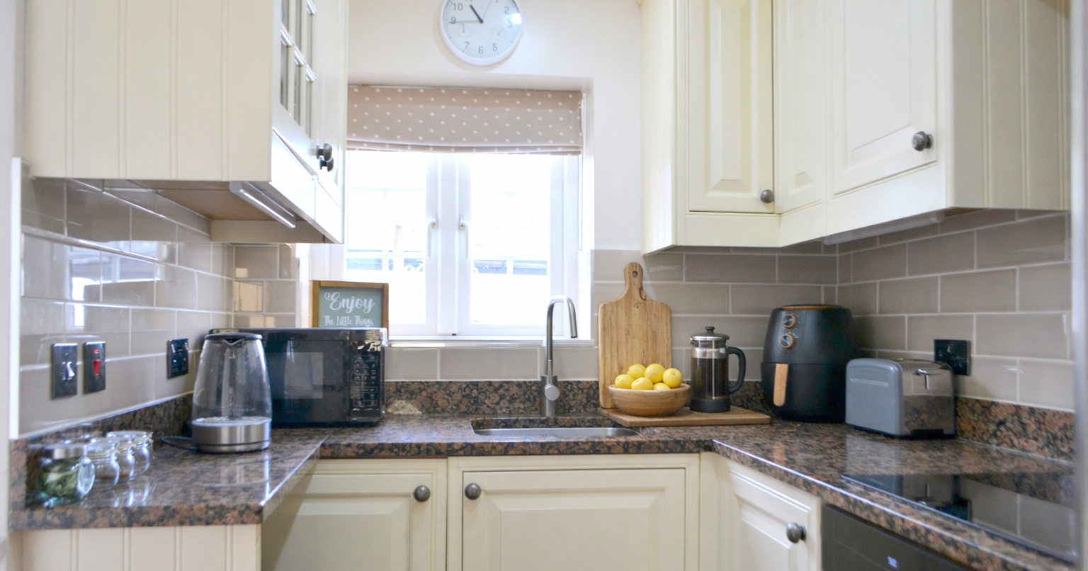 Cozy kitchen with French press, lemons, and various appliances on granite countertops.
