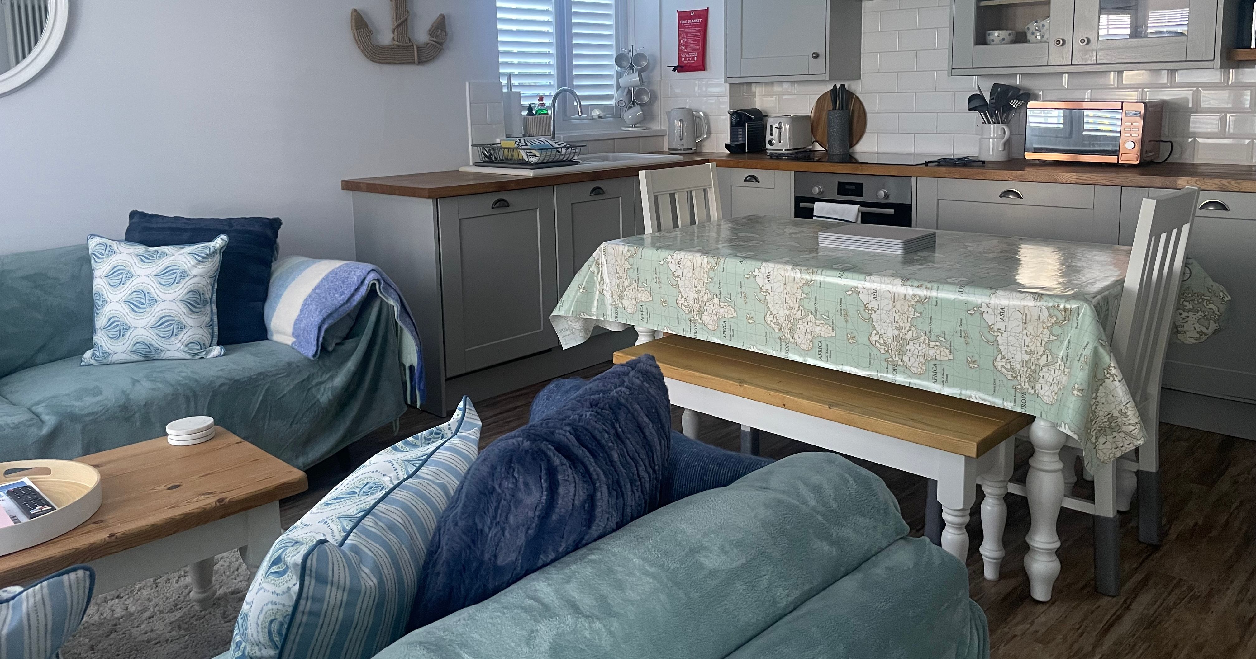 Cozy living room and kitchen with nautical decor and light blue furniture.