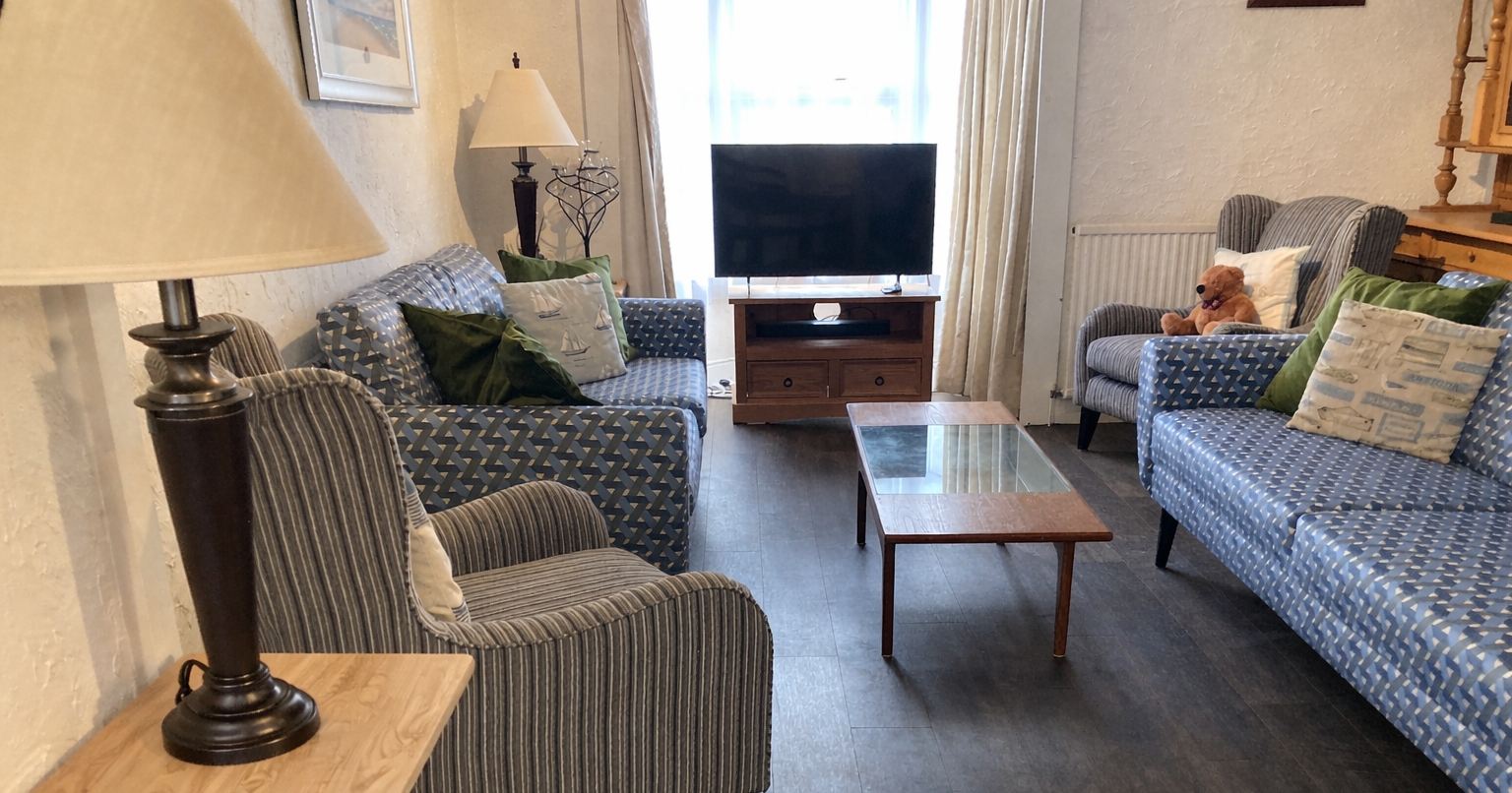 Cozy living room with patterned sofas, armchairs, a coffee table, and a TV.
