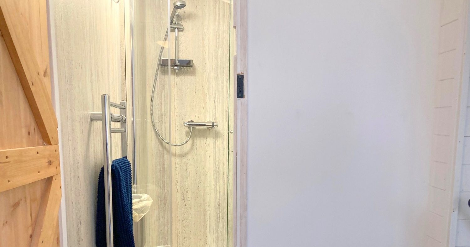 Modern shower cubicle with glass doors and chrome fixtures in a bright bathroom