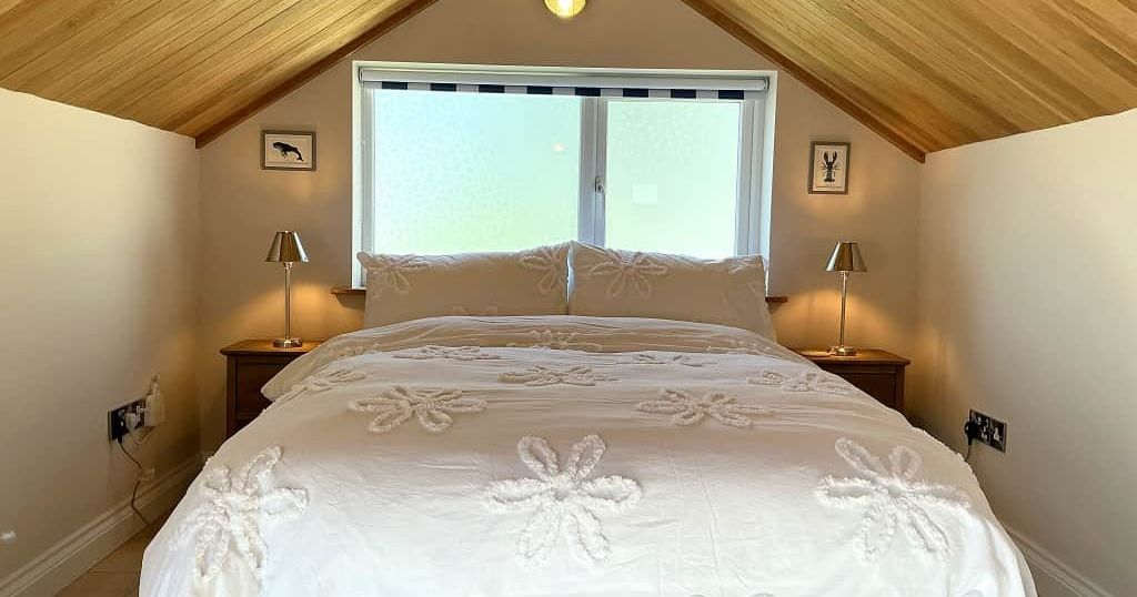 Cozy attic bedroom with wooden ceiling, double bed, and bedside tables