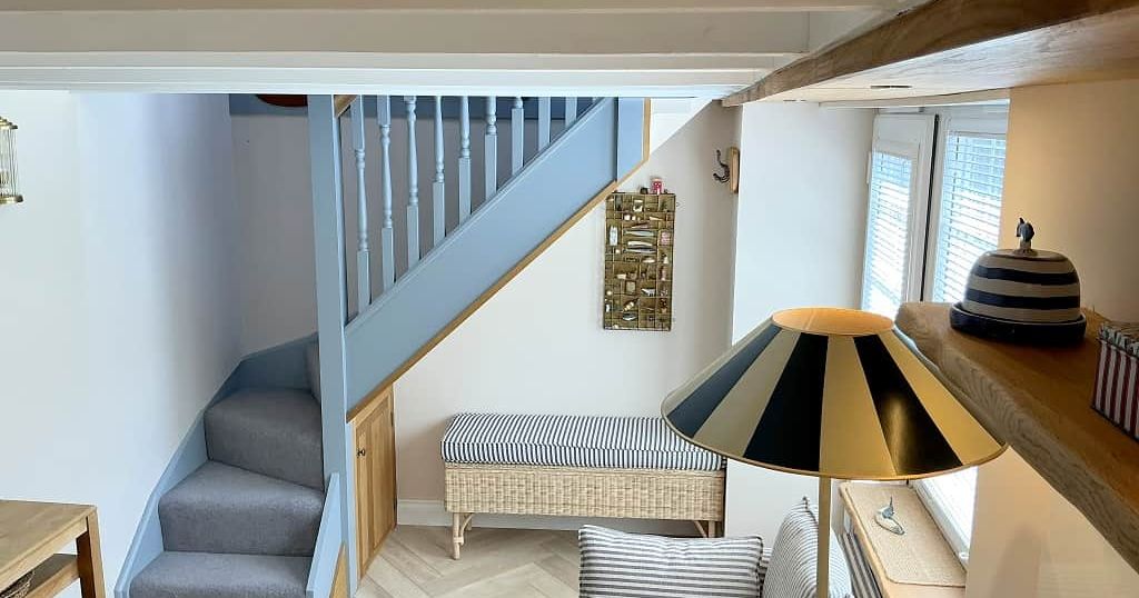 Cozy living room with blue staircase, striped sofa, and striped lampshade