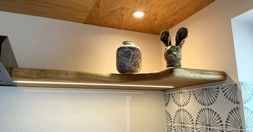 A wooden oak shelf with a vase and a decorative rabbit head ornament displayed on it