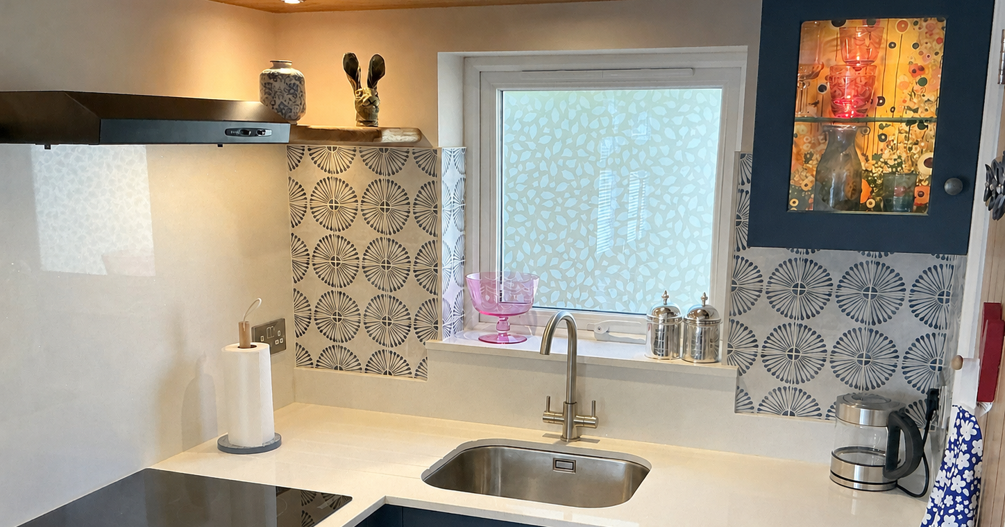 Modern kitchen with a white quartz worktop, blue cabinets, patterned tiles, and stainless steel sink.