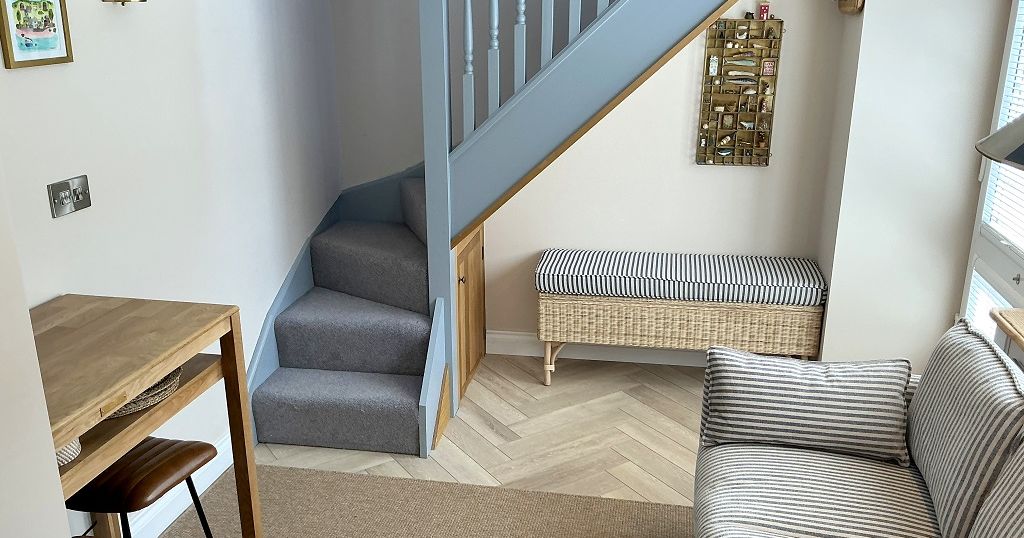 Modern living space with a striped sofa, small dining table, and staircase.