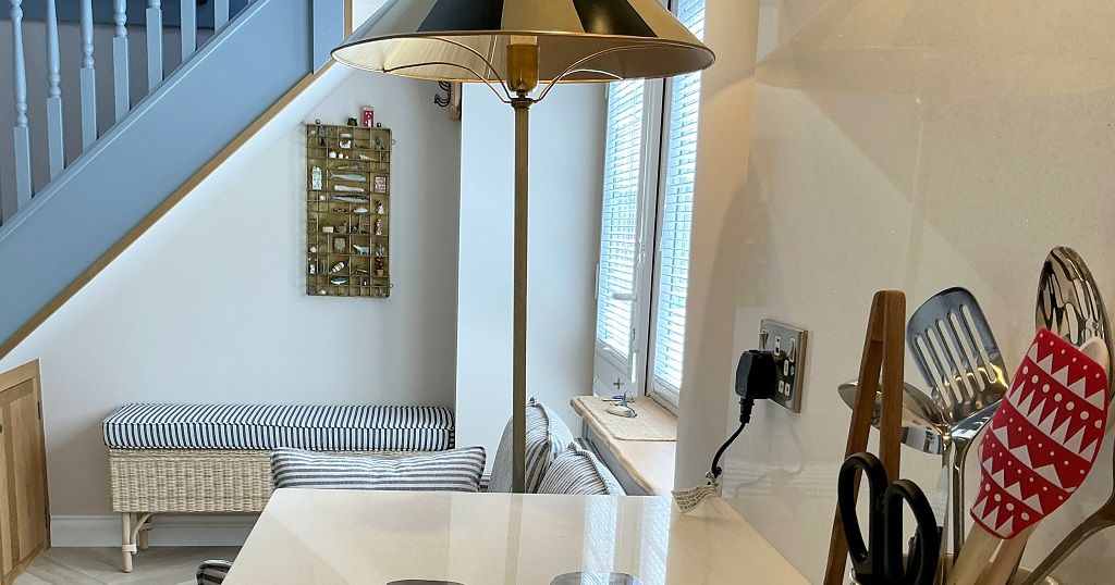 Kitchen worktop with utensils holder and view of an entrance area with striped bench under stairs
