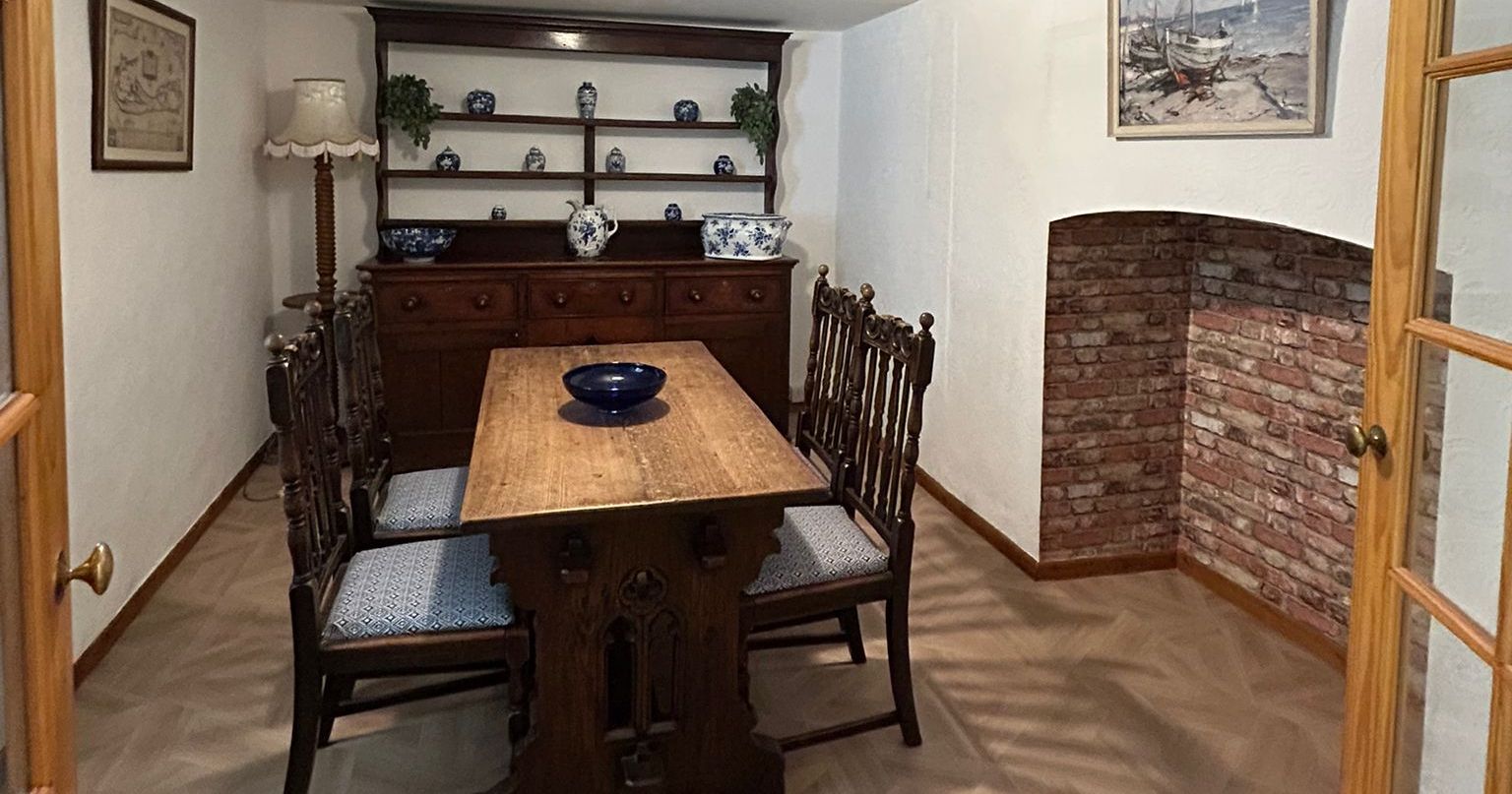 Cozy dining room with wooden table and chairs, brick alcove, and vintage decor