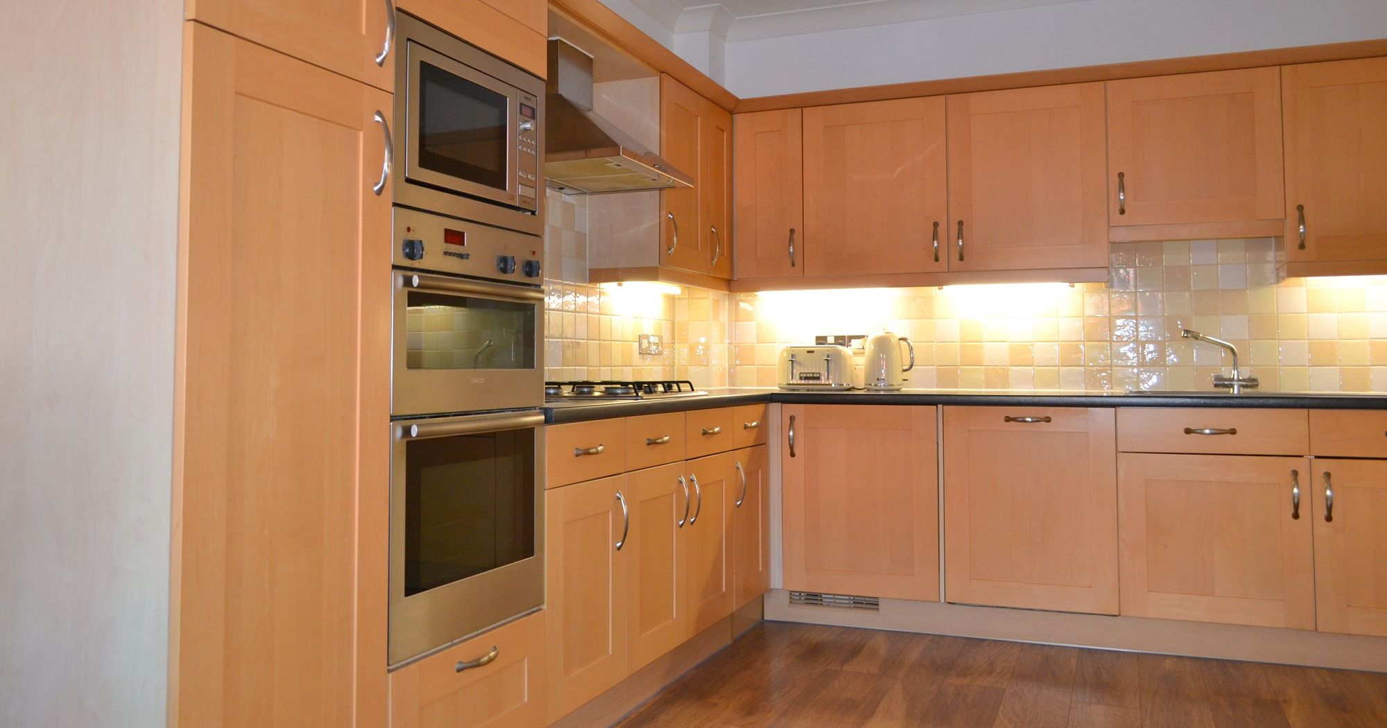 Modern kitchen with wooden cabinets, built-in oven, microwave, and countertop appliances