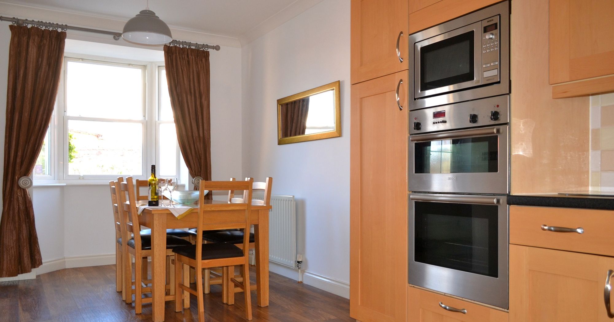 Modern kitchen and dining area with wooden furniture and built-in appliances