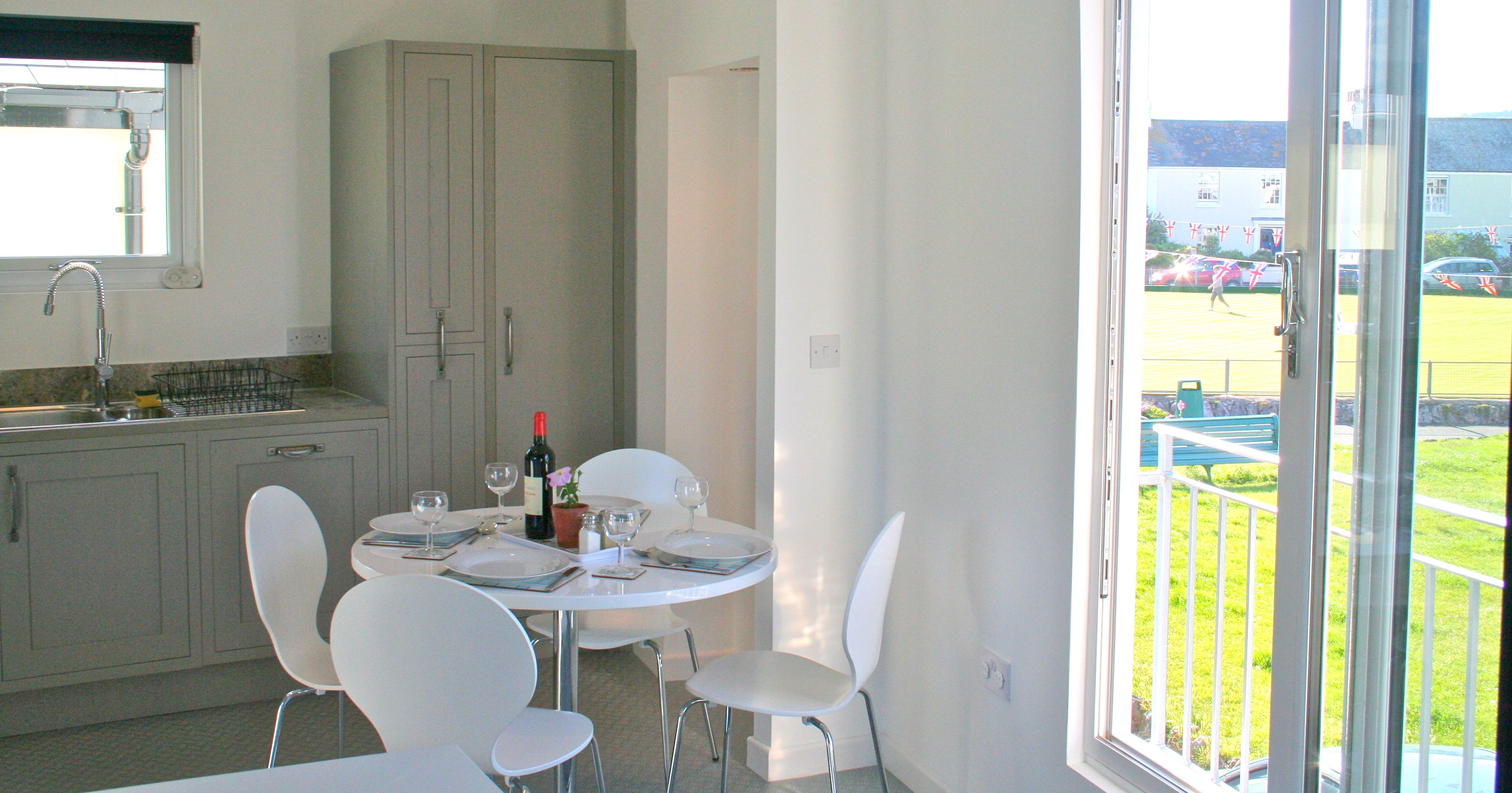 Modern dining area near a balcony with set table and kitchen in background