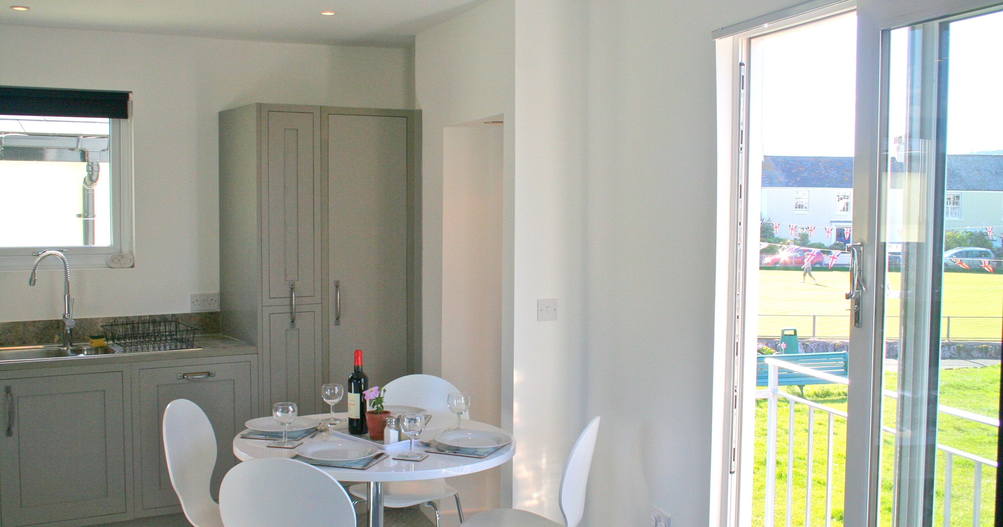 Modern dining area near a balcony with set table and kitchen in background