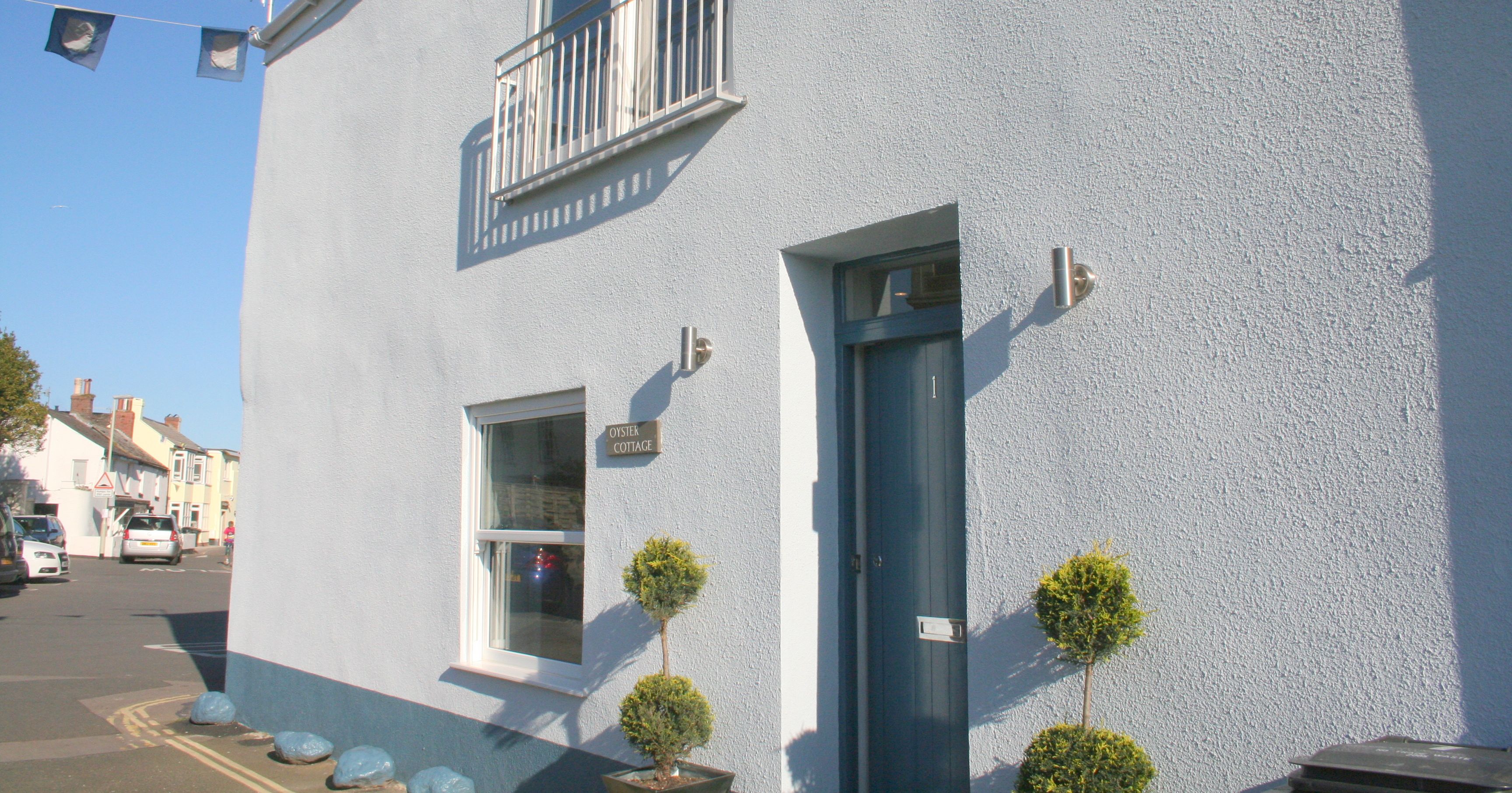 Exterior view of Oyster Cottage in Shaldon with blue door and small balcony