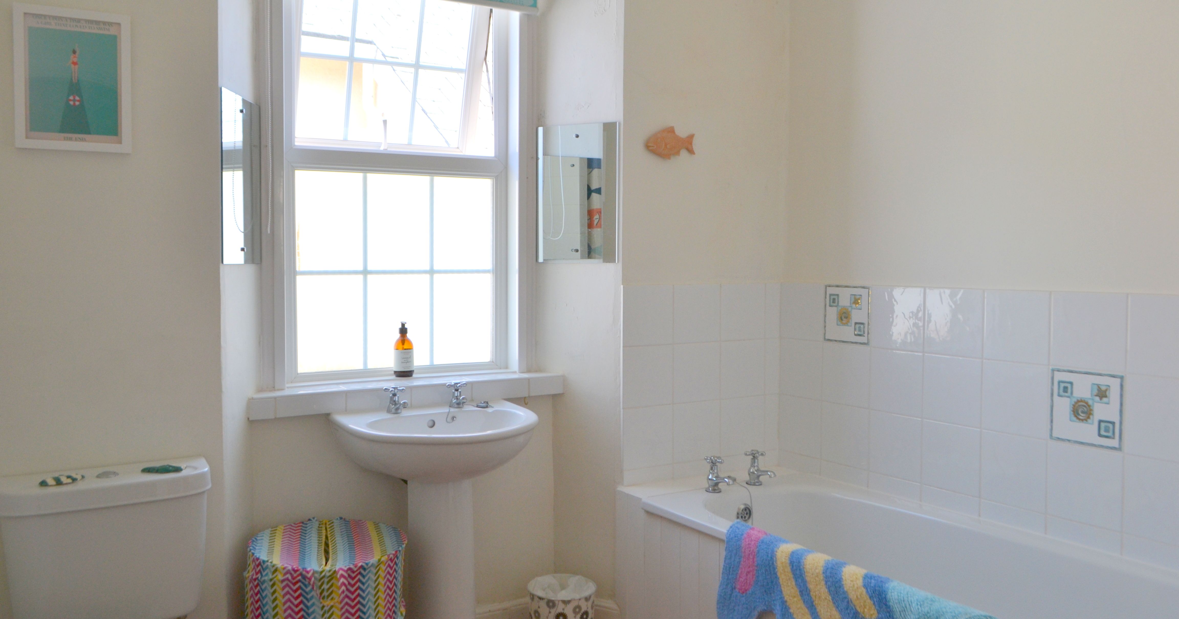 Bright bathroom with bathtub, sink, toilet, and colorful accessories