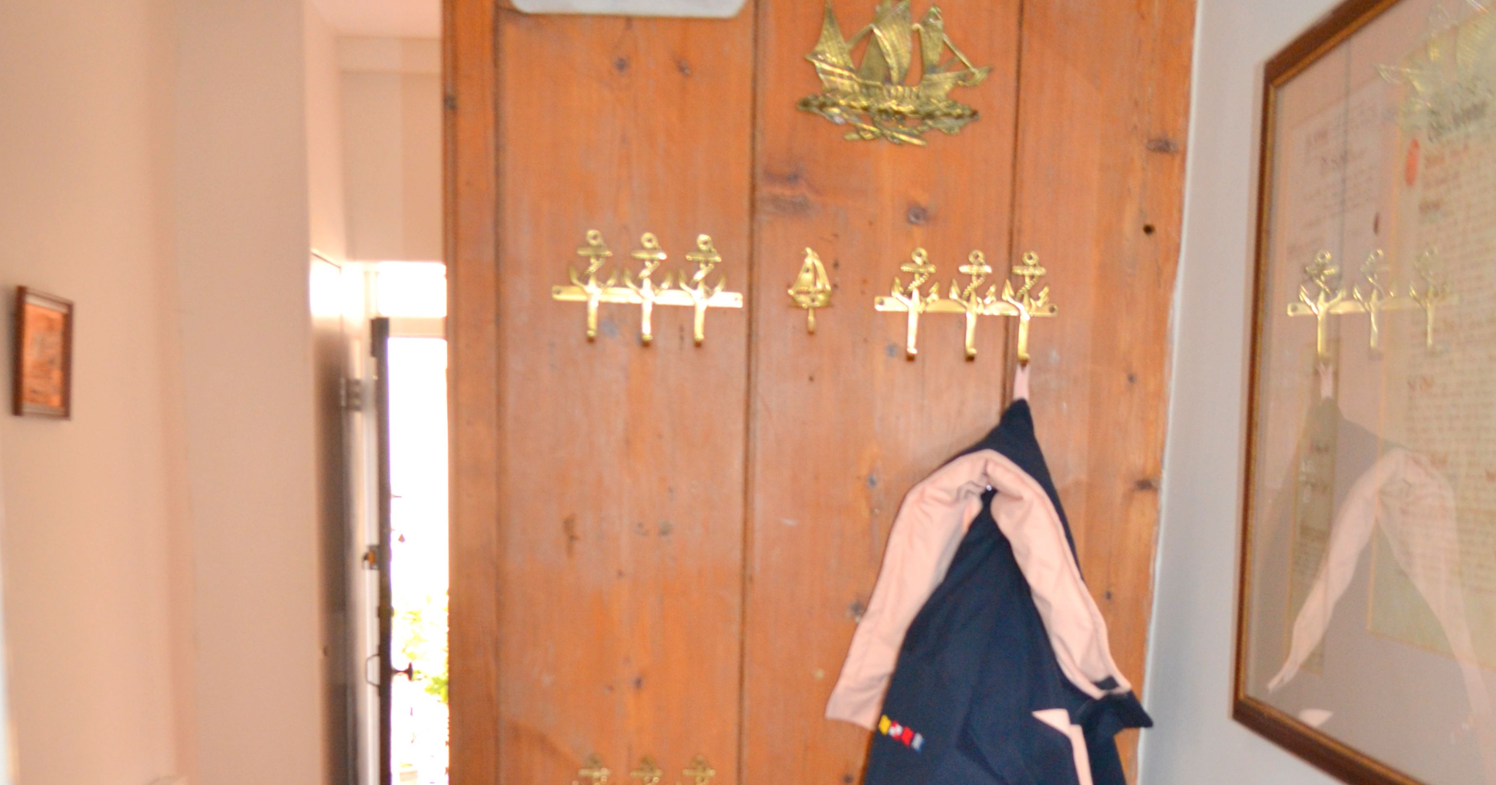 Wooden coat rack with jackets and a small bench in a hallway