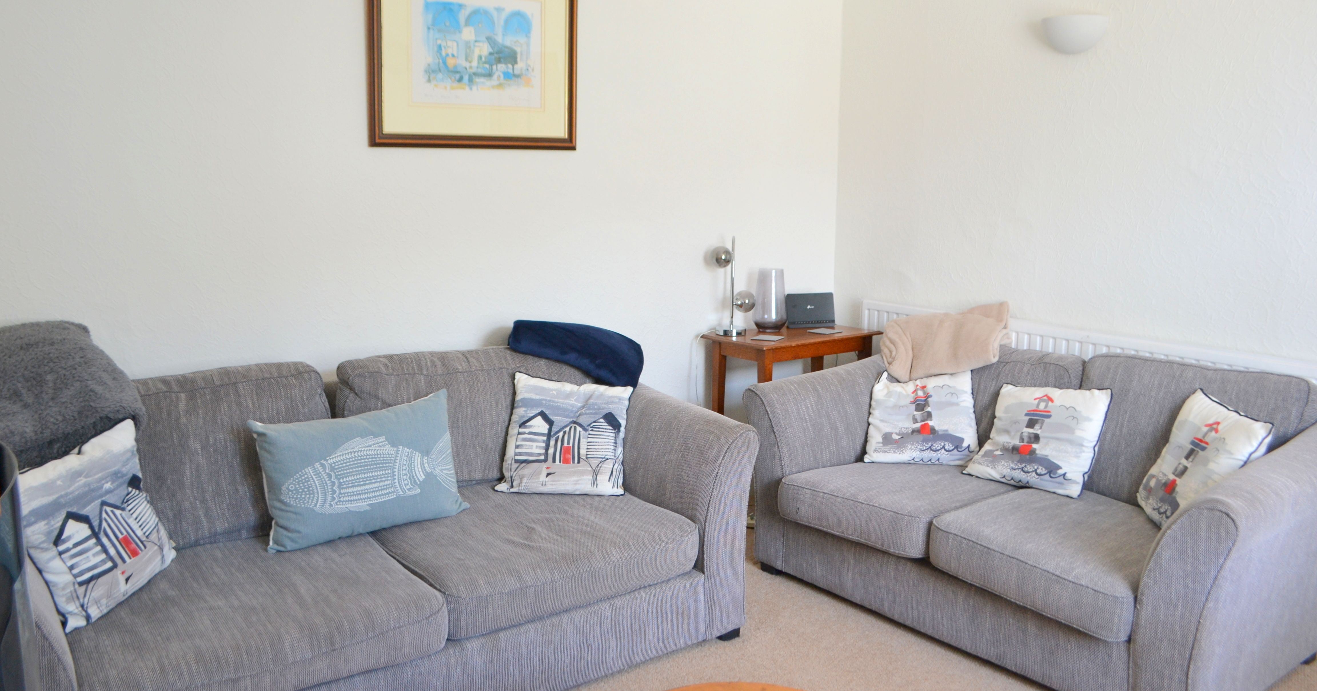 A cozy living room with two grey sofas, decorative pillows, and a framed picture on the wall.