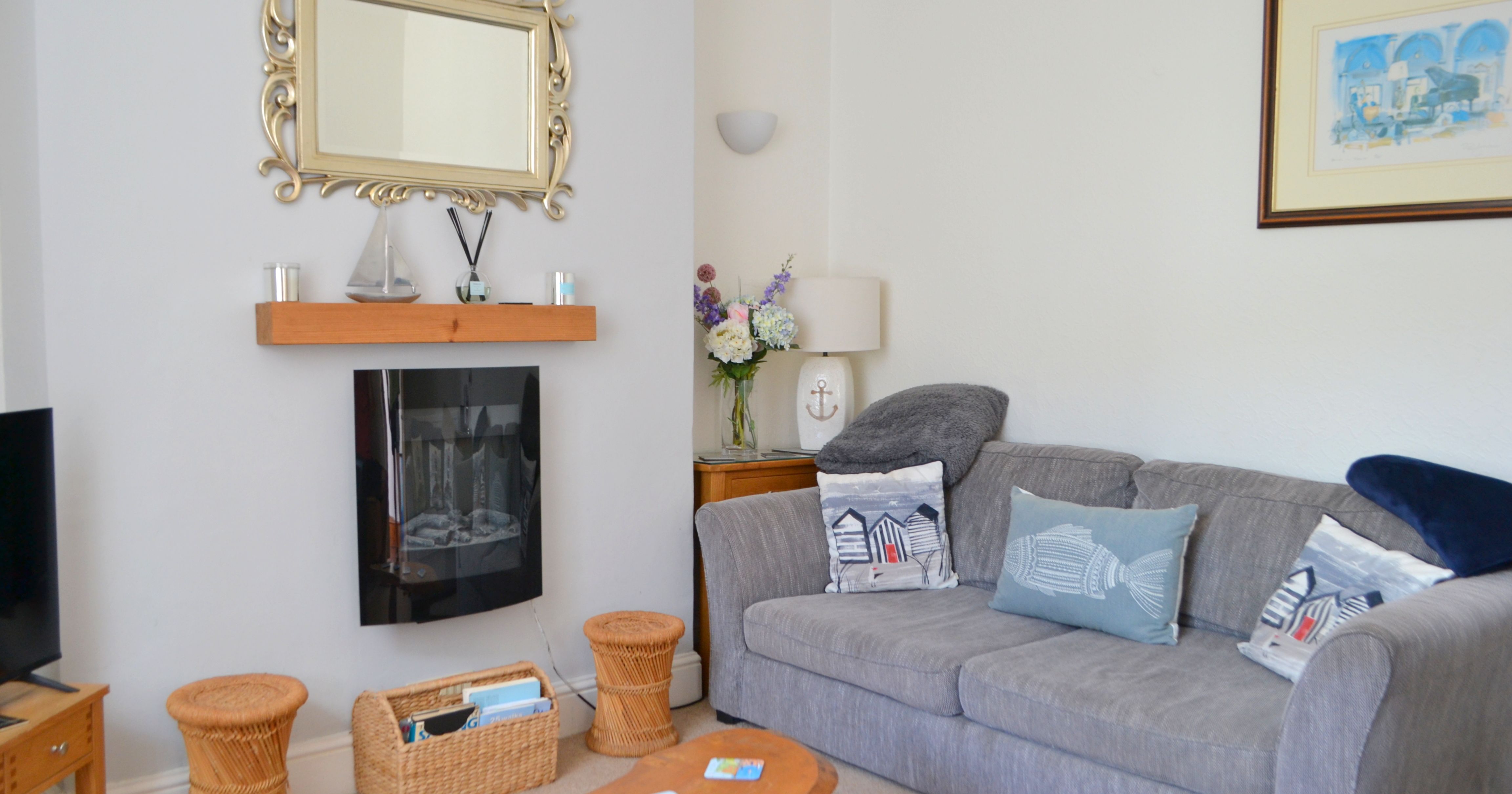 Cozy sitting room with grey sofa, fireplace, and nautical decor