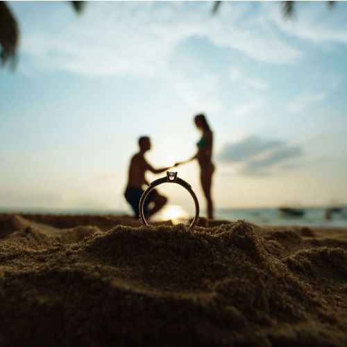 Wedding ring in the sand with a background of a proposal