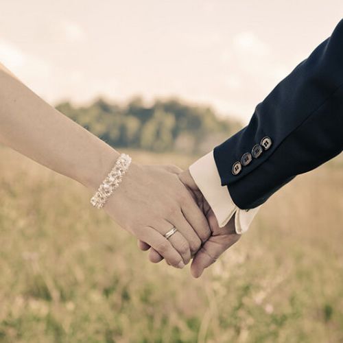 Bride and Groom holding hands in a grass field