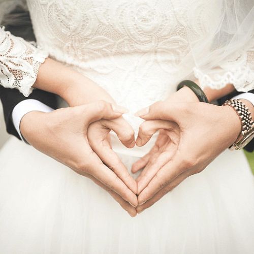 Groom and Bride making love hearts together with their hands