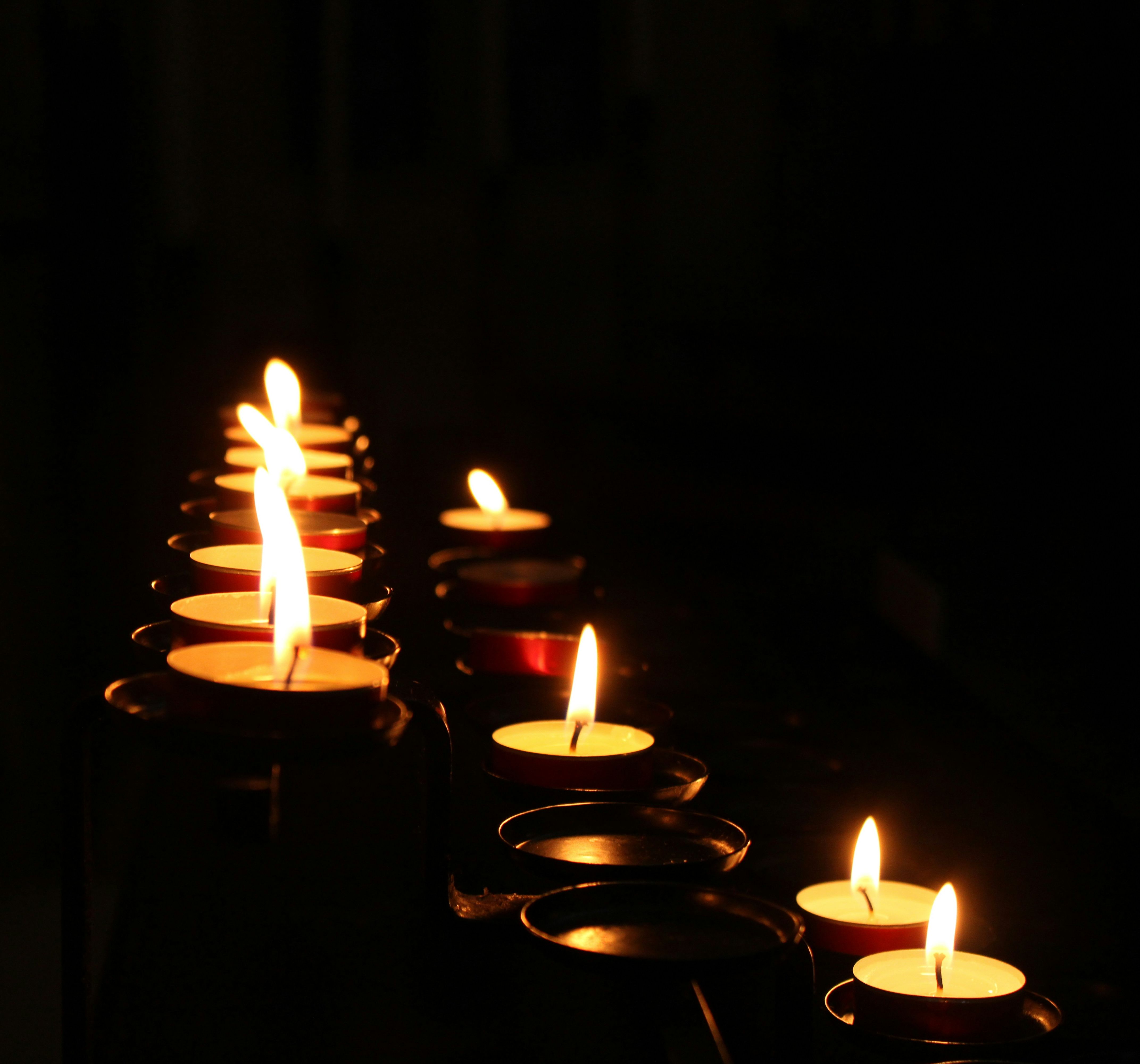 Row of lit candles in darkness