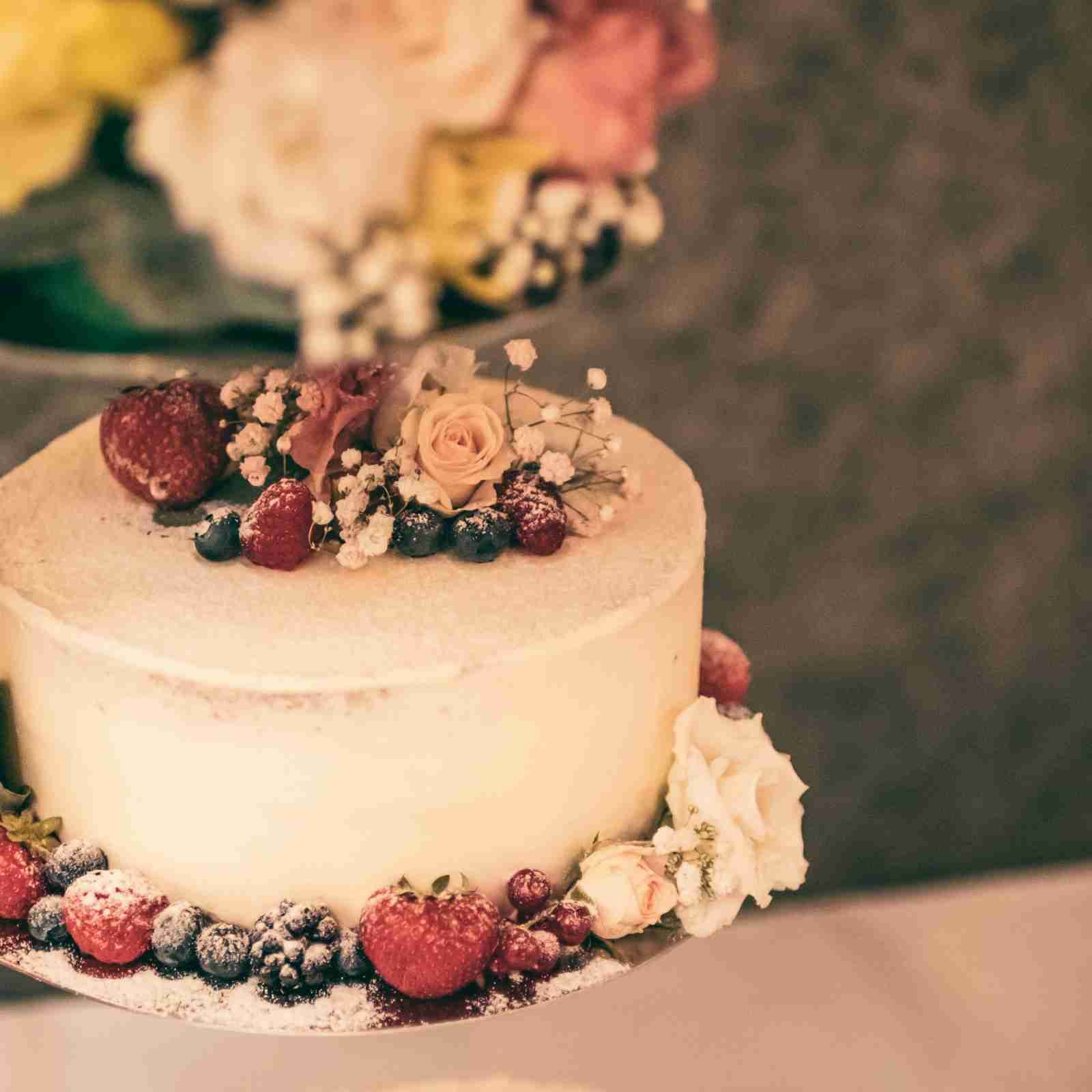 Two-tiered wedding cake decorated with fresh berries and flowers