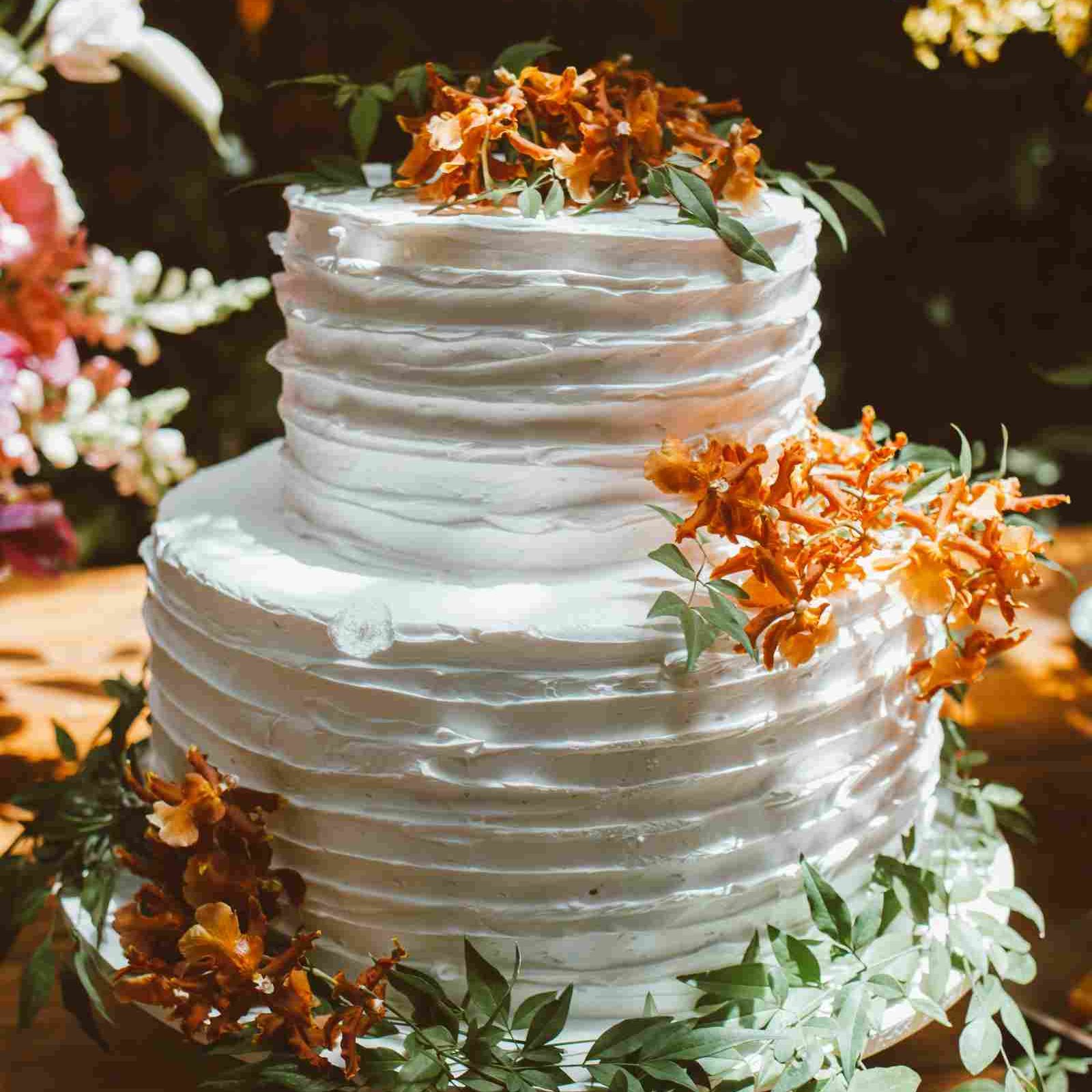 Two-tiered wedding cake decorated with orange flowers and green leaves