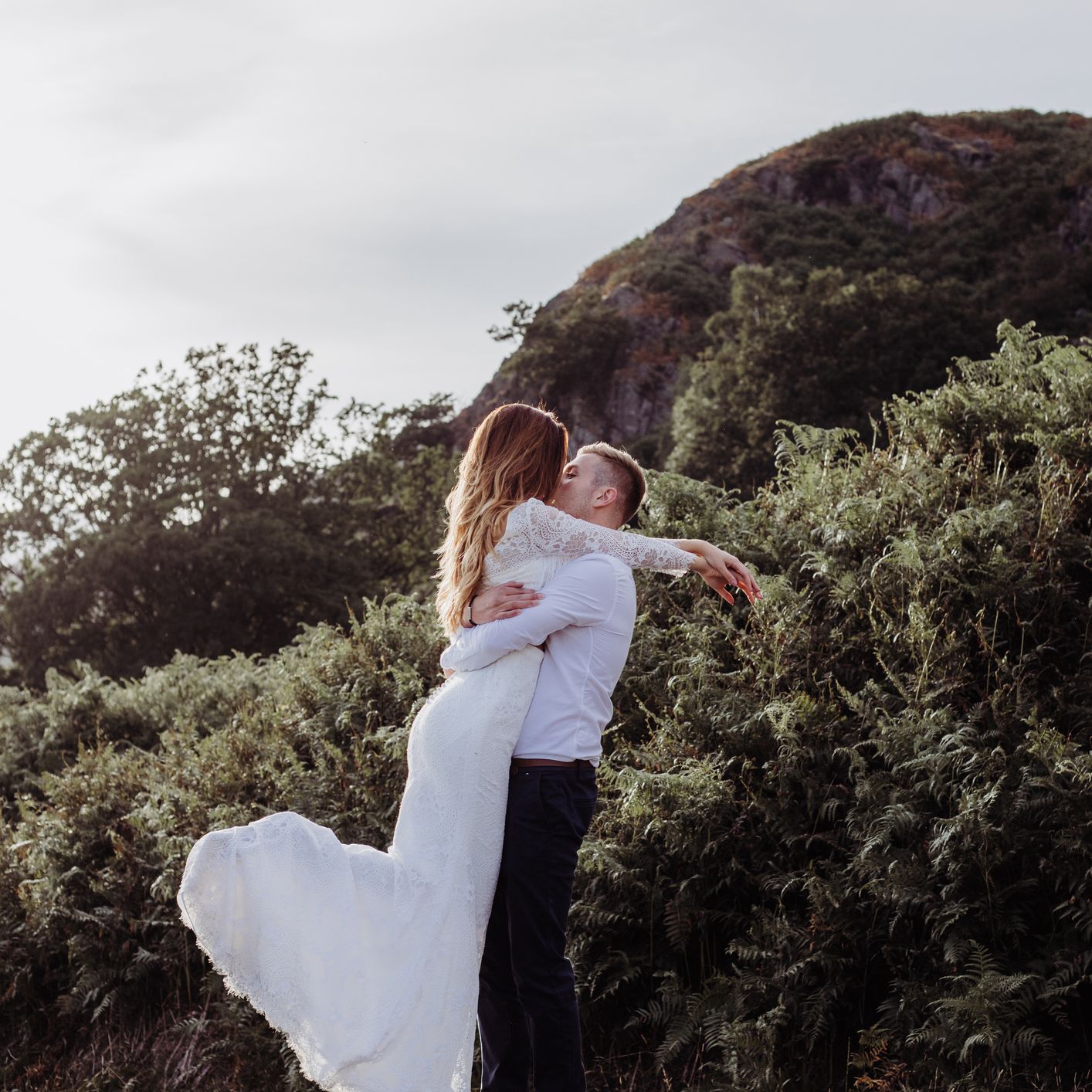 Bride and groom embracing in a lush hillside landscape