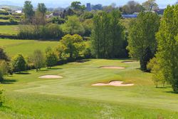 Golf course with sand bunkers and surrounding trees in a rural area