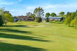 Golf course with clubhouse and trees on a sunny day