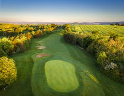 Aerial view of a golf course hole surrounded by lush green trees and fields