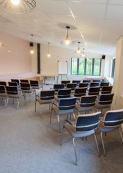 Empty conference room with rows of chairs facing a whiteboard and windows.