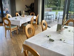 Tables set up for a baby shower in a bright room with large windows and wooden chairs.