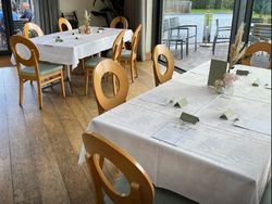 Tables set up for a baby shower in a bright room with large windows and wooden chairs.