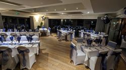Formal event dining room with long tables and chairs decorated in blue and white linens and ribbons.