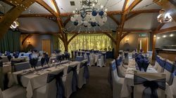 Elegant banquet hall decorated with white and navy blue, featuring balloons and string lights on the ceiling.