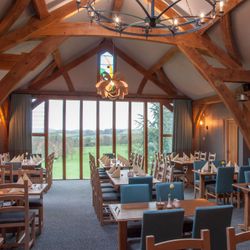 Spacious restaurant dining area with wooden beams and large windows overlooking a scenic landscape.